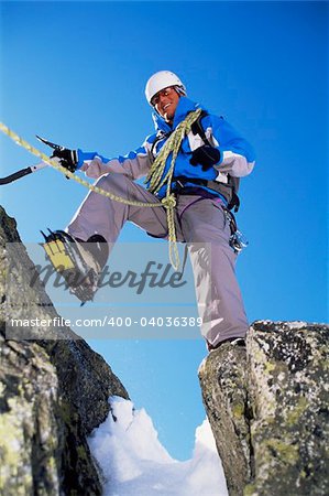 Young man mountain climbing on snowy peak