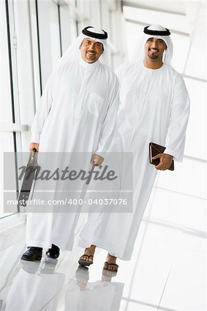 Two Middle Eastern businessmen walking in a corridor