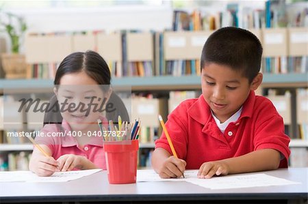 Kindergarten children sitting at desk and writing in classroom