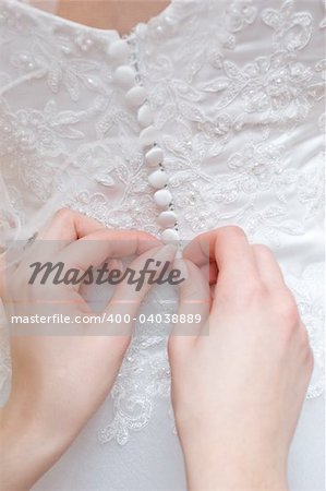 hands of girls help to the bride to button wedding dress