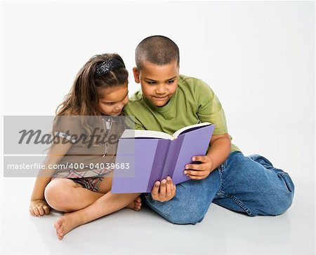 Hispanic brother and sister reading book together.