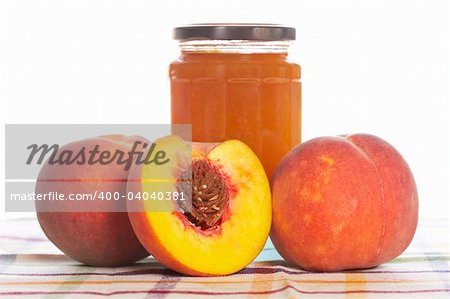 Peach jam glass jar and some fresh fruits on square mat. Shallow depth of field