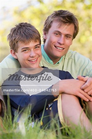 Man and young boy sitting outdoors smiling