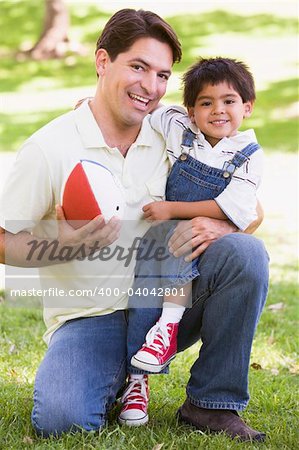 Man and young boy outdoors with football smiling