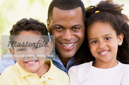 Man and two young children outdoors smiling