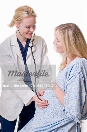 Pregnant blond woman being examined by a female doctor holding a stethoscope on the stomach