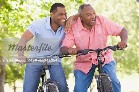 Two men on bikes outdoors smiling