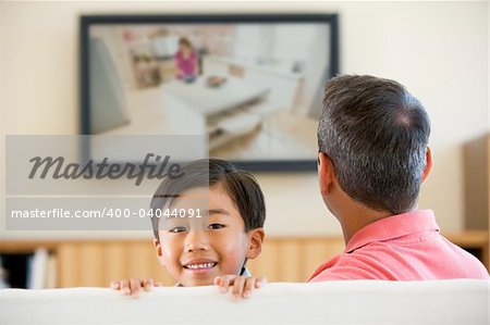 Man and young boy in living room with flat screen television smi