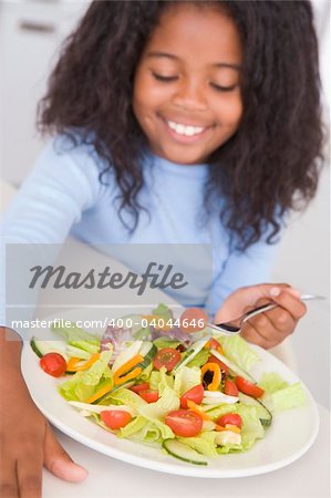 Girl sitting at table eating salad at home