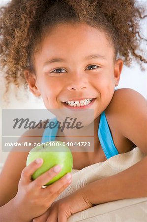 Young girl eating apple in living room smiling