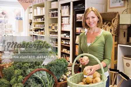 Woman in market looking at potatoes smiling