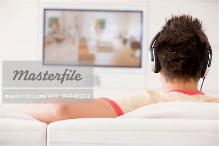 Man in living room watching television and wearing headphones