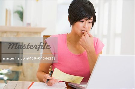 Woman in dining room with laptop thinking