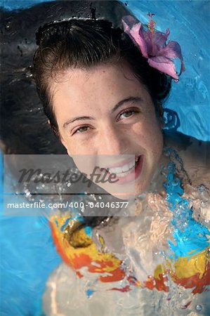 Pretty teen girl with a fower in a pool