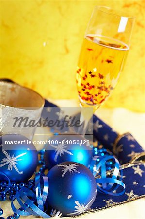 Christmas decoration with champagne bottle and full glass over colour background. Shallow depth of field