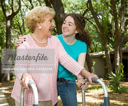 Vibrant senior lady with walker and hearing aid laughing with her teen-aged granddaughter.
