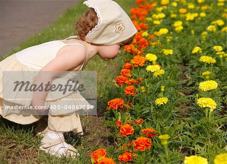 A little girl is smelling the blooming folwers.