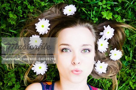 Summer Kiss. Woman with flower in hair laying on grass.