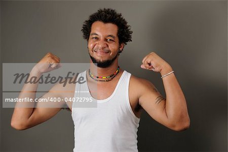 Portrait of young happy latino man showing his strong muscles