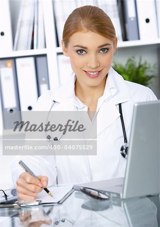 Smiling female doctor writing notes in clipboard