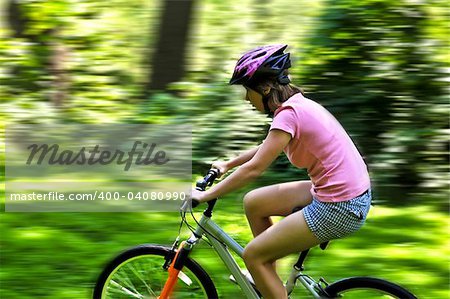 Portrait of a teenage girl riding a bicycle in summer park outdoors