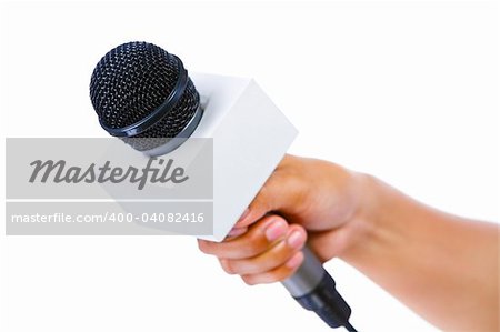 Side view of a bare hand holding a microphone aiming to the empty space on left. Shallow depth of field, focus mainly on microphone's tip.