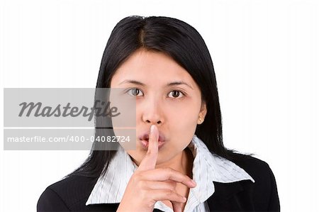 A woman acting to tell us to be quiet against the camera. Shoot agaisnt very bright white background to eperate the model and background naturally.