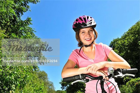 Portrait of a teenage girl on a bicycle in summer park outdoors