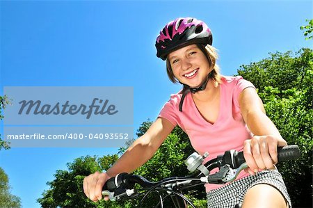 Portrait of a teenage girl on a bicycle in summer park outdoors