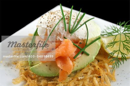 Beautiful salmon and poached egg stack on a hash brown with avocado.