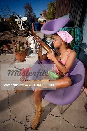 Black woman kissing rifle in front of house with messy yard
