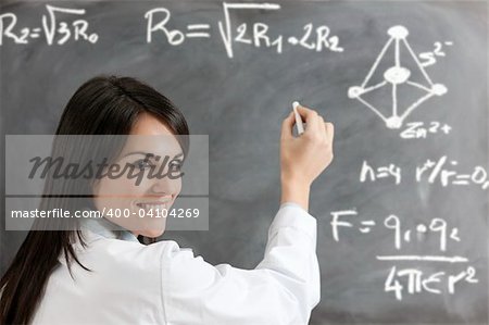 portrait of mid adult woman writing chemical formula on blackboard