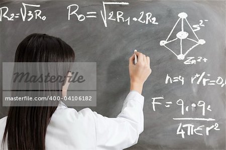 portrait of mid adult woman writing chemical formula on blackboard