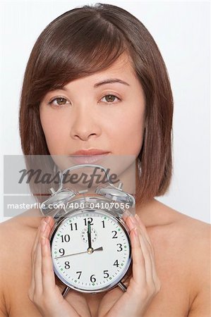 A naturally beautiful oriental woman make up free and holding an alarm clock