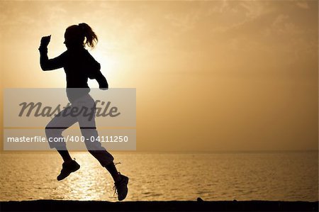 Young woman running on a sunset beach background