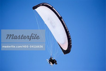 A paraglider isolated against a deep blue sky