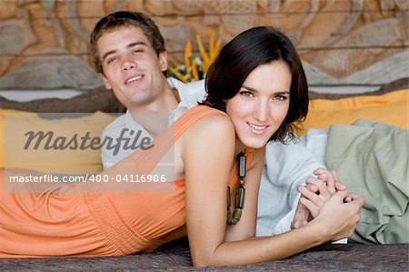 A young attractive couple on vacation lying on a daybed