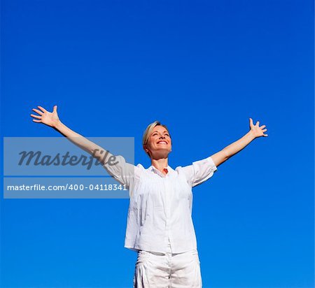 Young woman doing exercises outdoors against blue sky