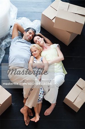 Parents and daughter lying on the floor of their new house