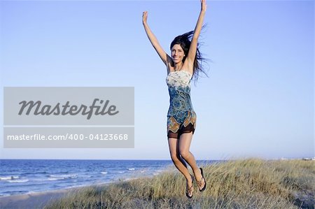 Beautiful brunette jumping in the summer blue beach