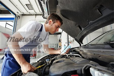 side view of mechanic checking motor oil