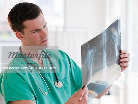 A young male doctor is looking at some x-rays.  Horizontally framed shot.