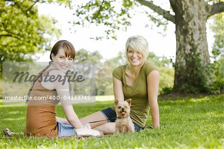 Young women sitting with dog at a park