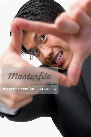 Portrait of Asian businessman looking at his perspective by framing his fingers to the camera
