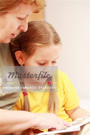 Cute little girl reading a book with her grandmother