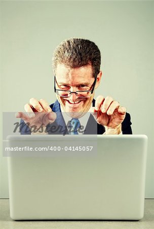 Crazy businessman working at desk on laptop computer