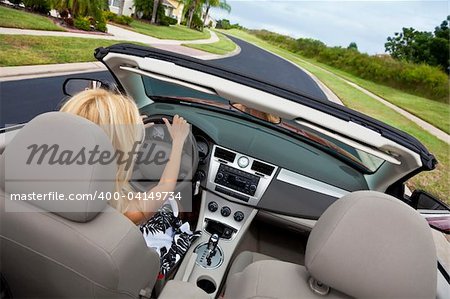 Rear view of a beautiful young blond woman driving her convertible car