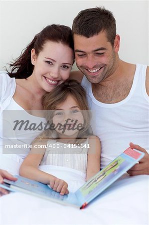 Parents and daughter reading together in bed