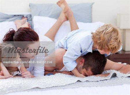 Happy young family playing together in bed