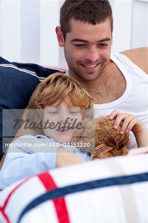 Portrait of father and son reading a book in bed together